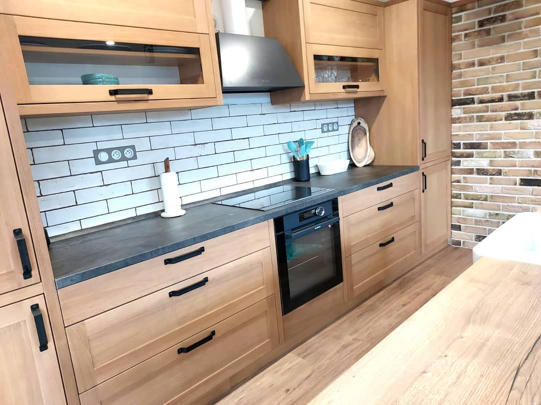 Rustic kitchen with wood cabinets, white subway tile backsplash, and brick accent wall.