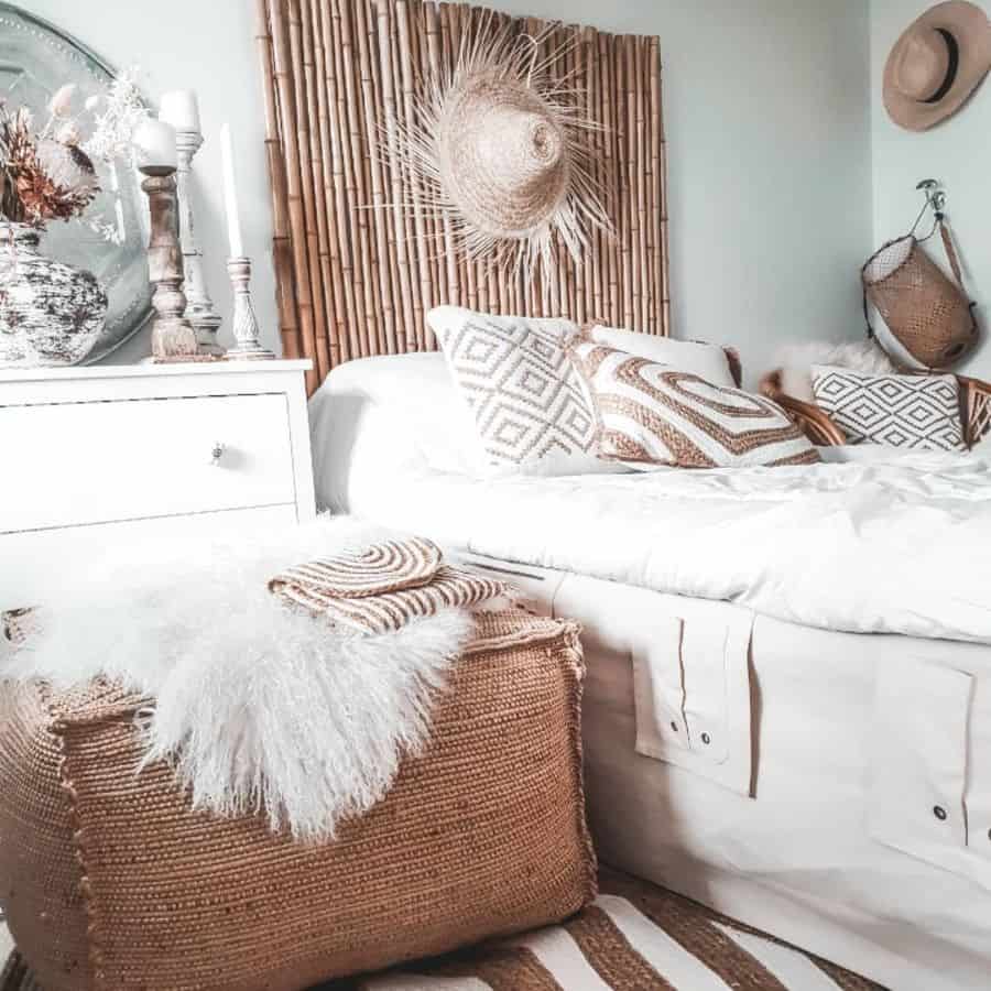 Boho bedroom with bamboo headboard, neutral pillows, woven accents, and rustic decor elements.