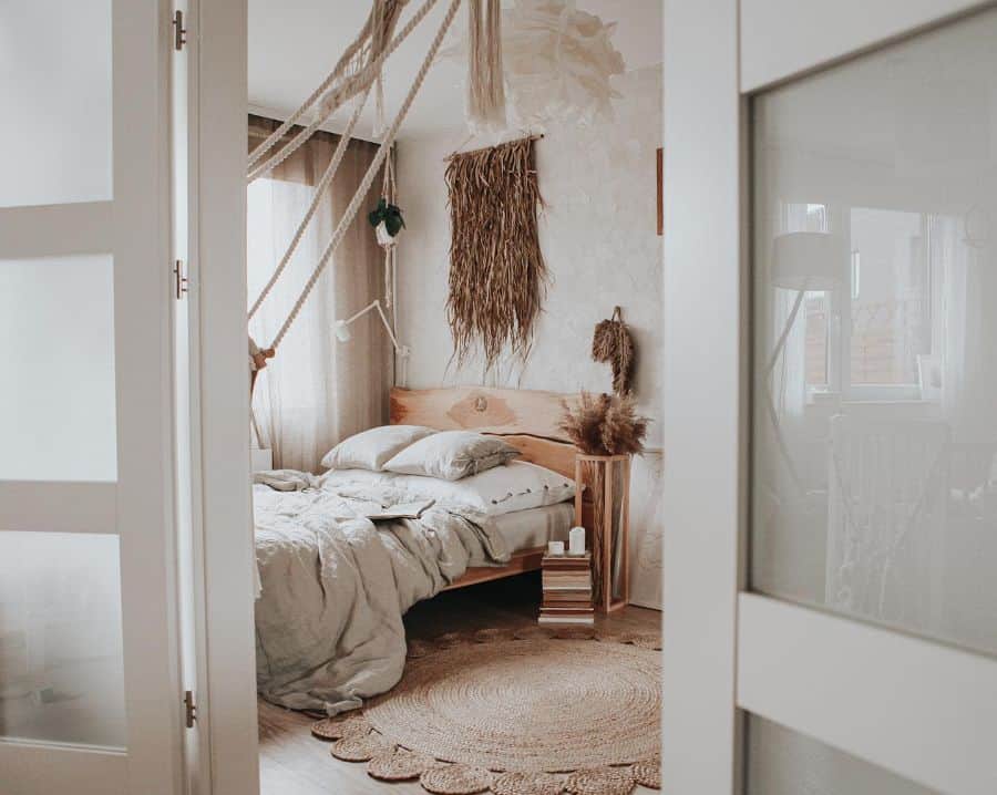 Rustic boho bedroom with natural wood bed, woven rug, and earthy wall decor accents.