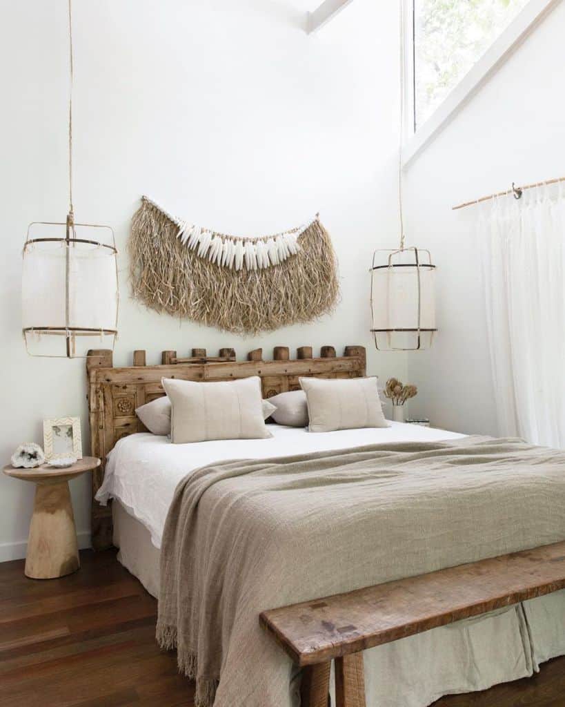 Boho bedroom with carved wooden headboard, neutral bedding, and hanging natural fiber decor.