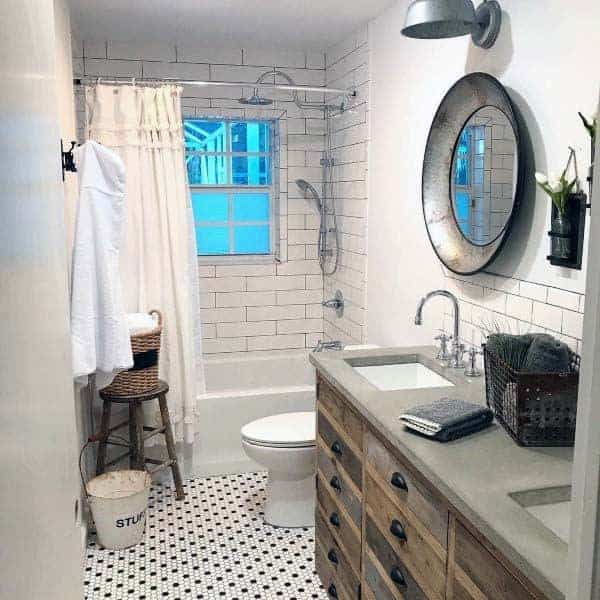 Rustic bathroom with wooden vanity, round mirror, white subway tiles, and patterned tile floor.