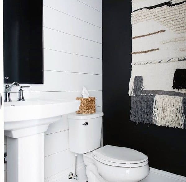 Charming black and white half-bath with shiplap walls, a woven rug, and minimalist fixtures.