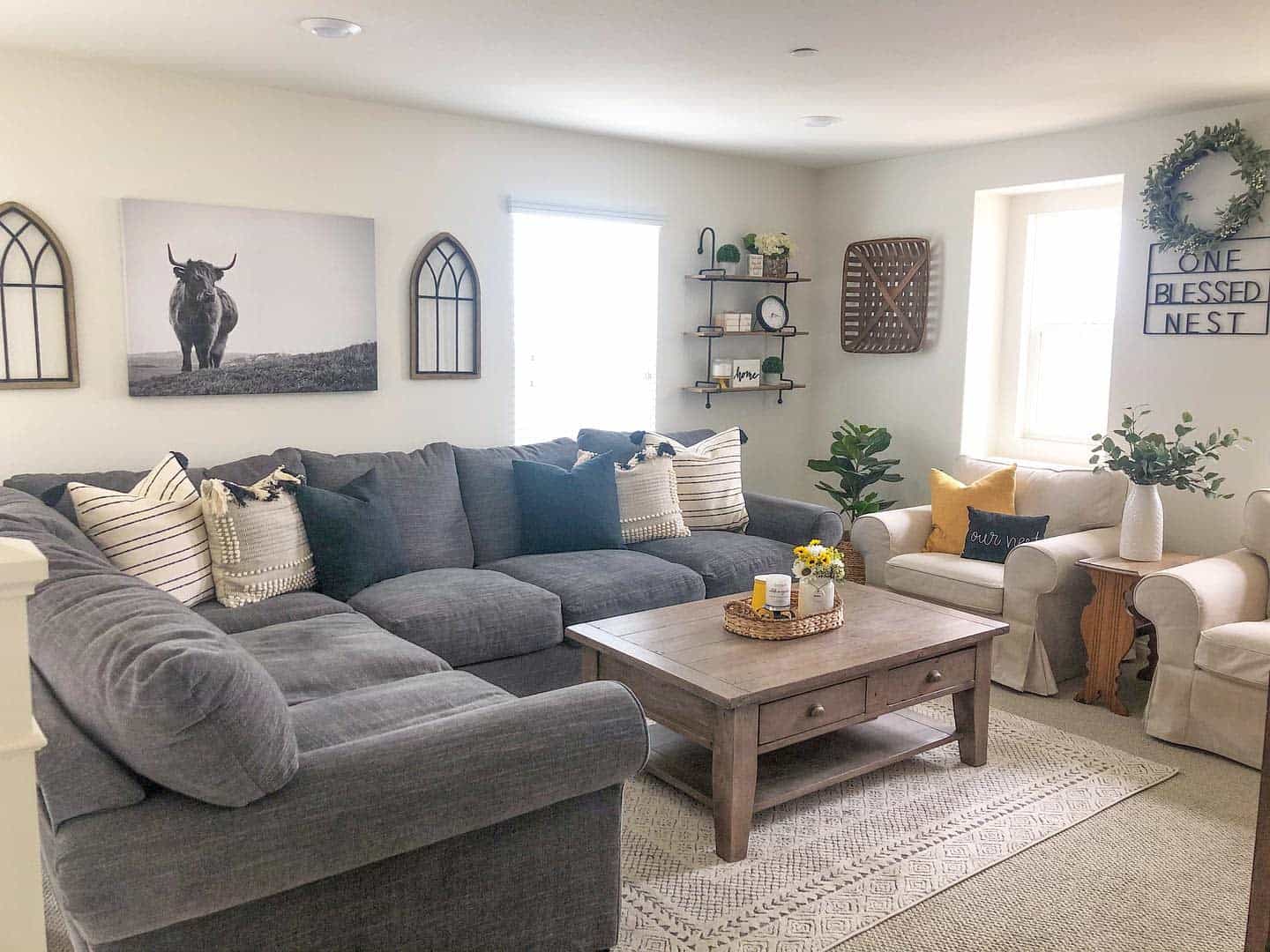 Rustic family room with grey sectional, farmhouse decor, wood coffee table, and neutral accents.