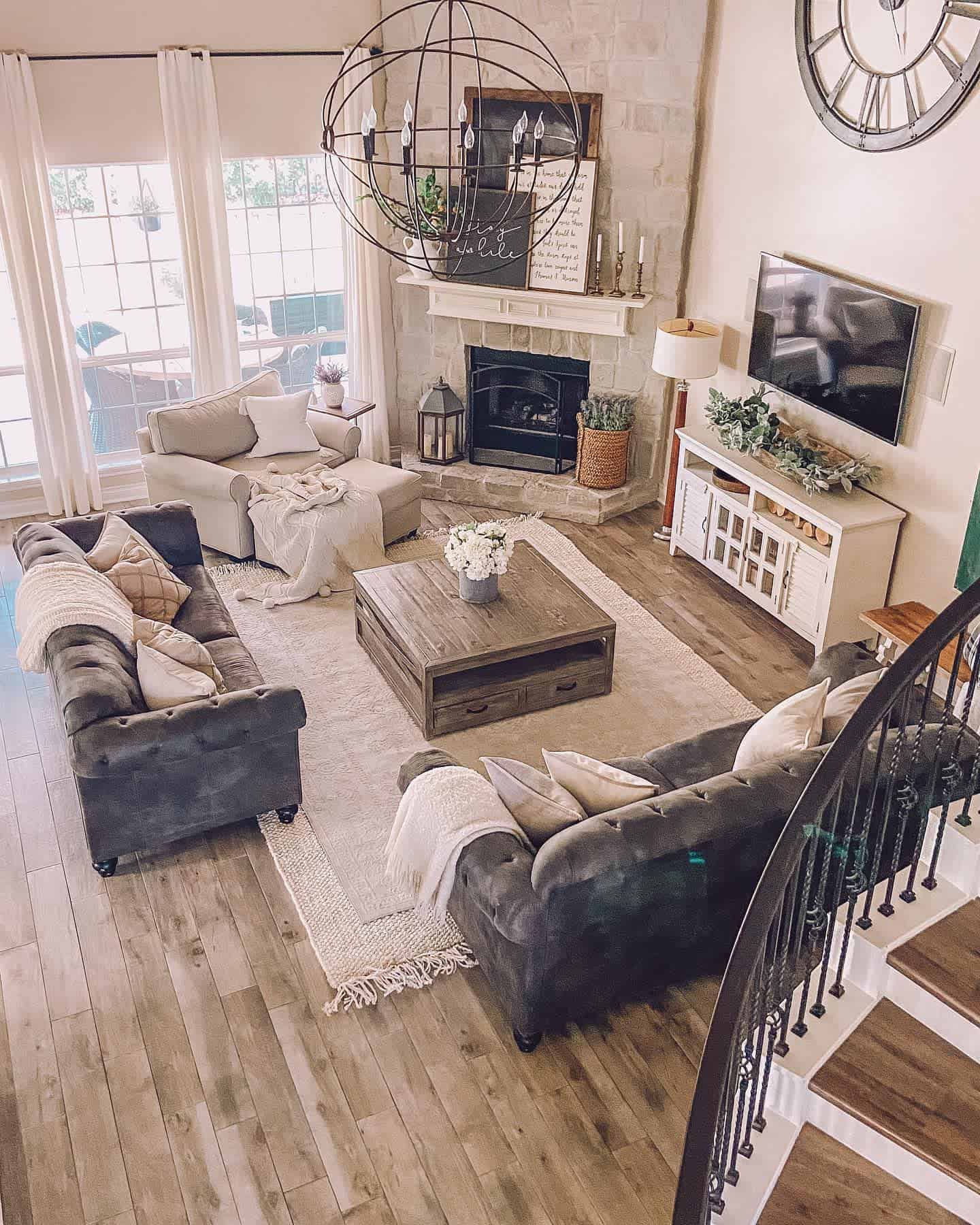 Cozy living room with sofas, a rustic coffee table, fireplace, TV, and large window, neutral decor and wood floors