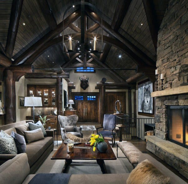 Rustic living room with vaulted wooden ceiling, stone fireplace, cozy sofas, and a central wooden coffee table