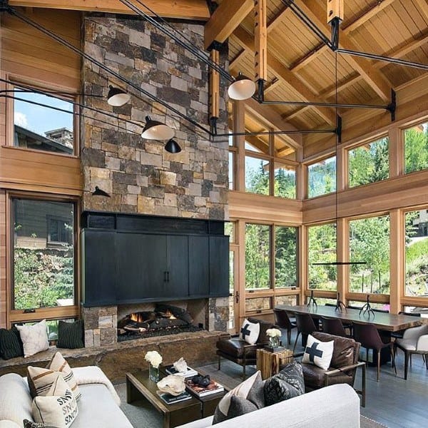 Spacious living room with stone fireplace, wooden beams, large windows, and modern furniture