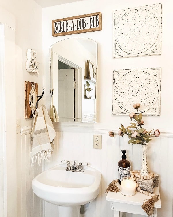 Retro-style bathroom sink with wall art, decorative vase, and "Scrub-A-Dub-Dub" sign.