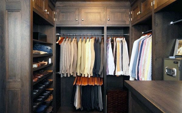 Walk-in closet with neatly organized clothes, shoes, and accessories on wooden shelves and hangers