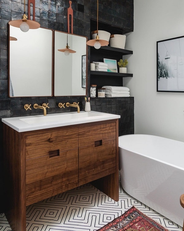 Modern bathroom with wooden double vanity, black tiled wall, floating shelves, and freestanding tub.