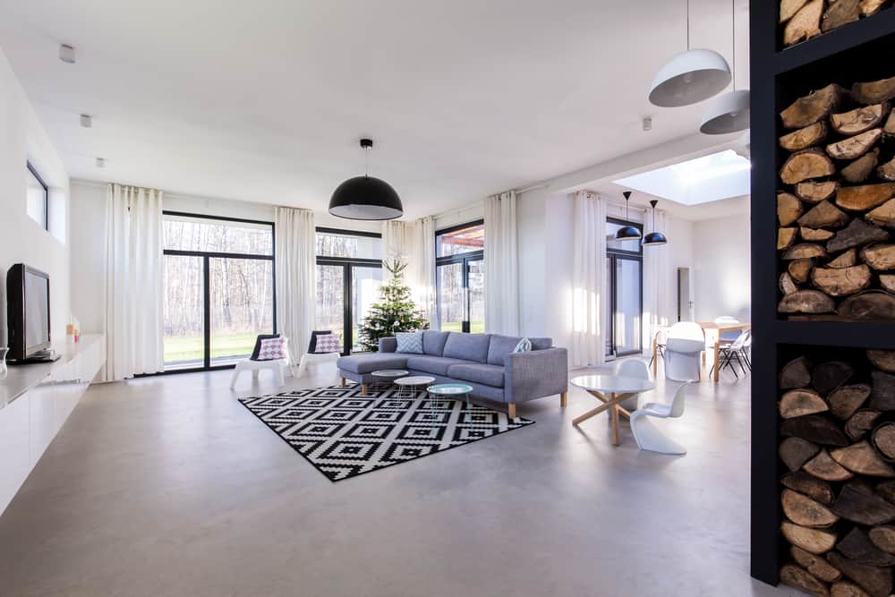 Spacious Scandinavian-style living room featuring a gray sofa, geometric rug, large windows, and wood accents for a cozy modern touch