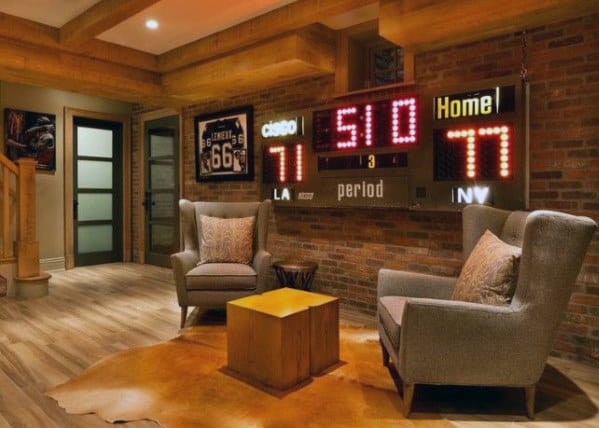 Rustic mancave with brick walls, vintage scoreboard, cozy armchairs, and wood beam ceiling.