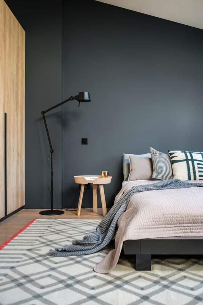 Minimalist bedroom with platform bed, geometric rug, and black floor lamp.