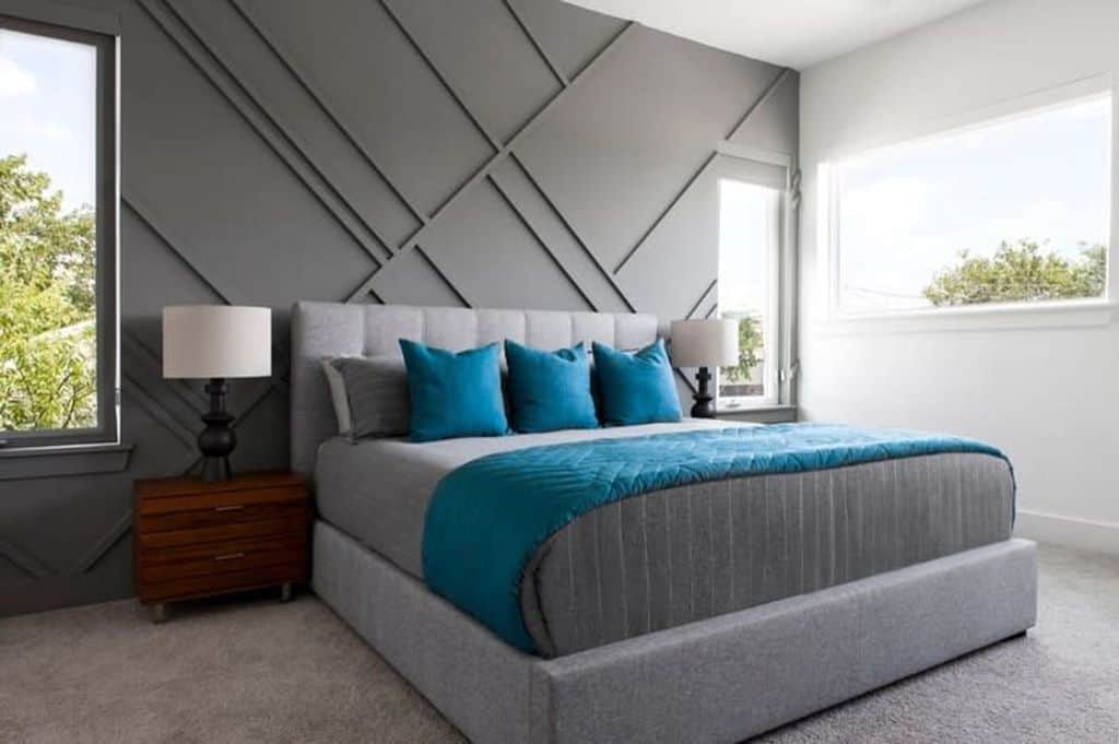 Modern bedroom with gray accent wall, upholstered bed, and blue throw pillows.