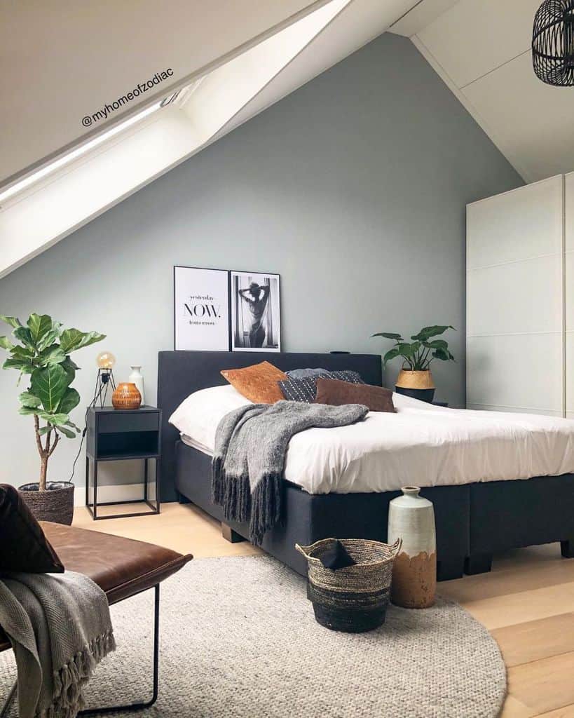 Attic bedroom with black bed, cozy decor, potted plants, and a light gray rug.