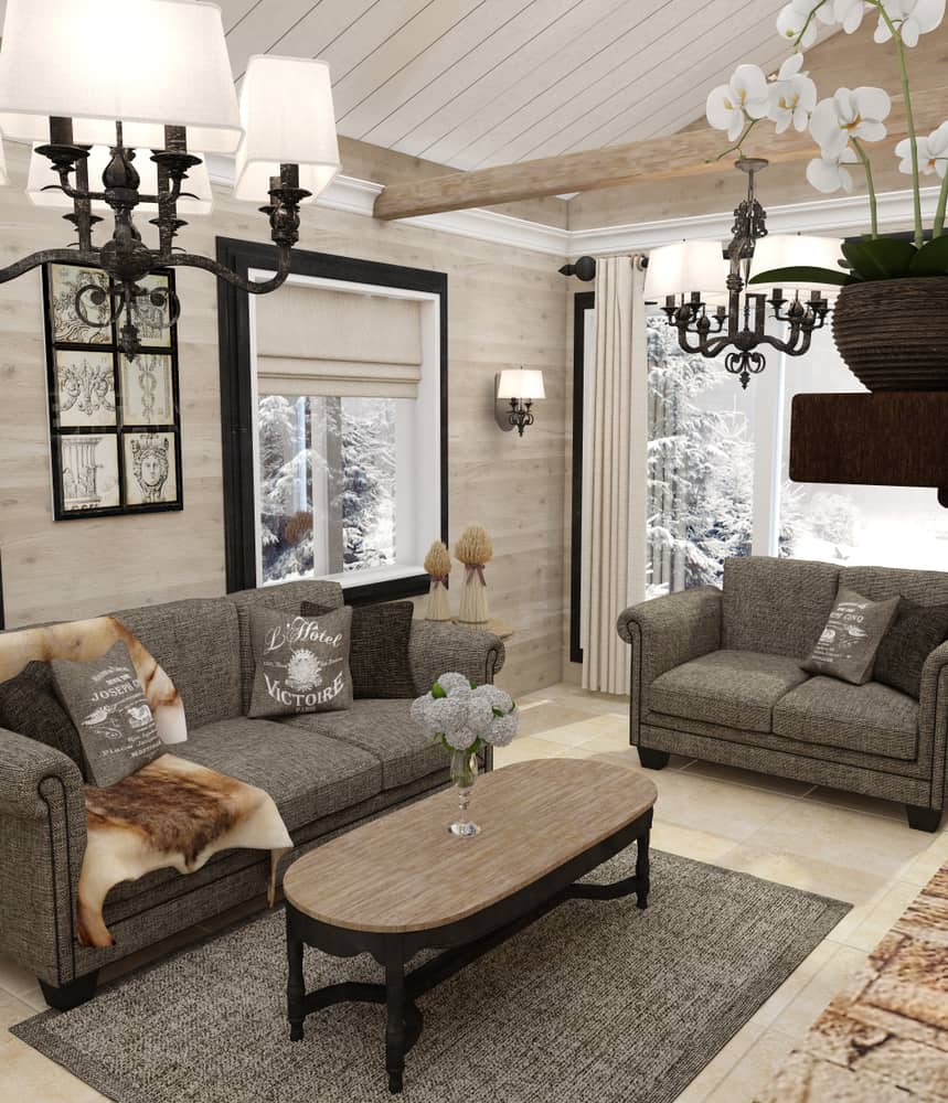 Cozy living room with sofas, a wooden coffee table, chandeliers, and a snowy view through the windows