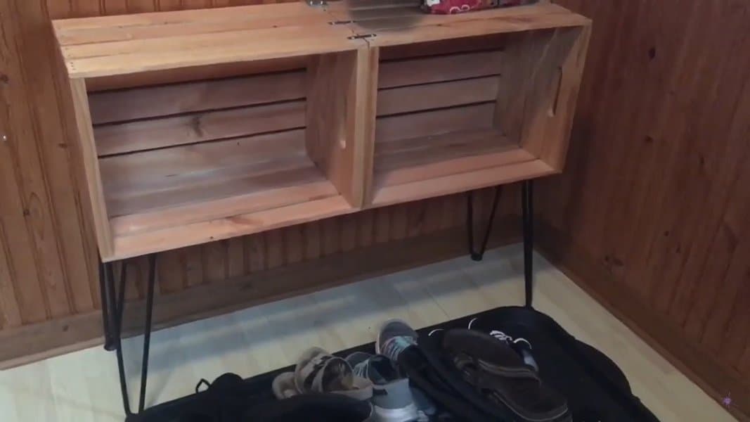 Rustic wooden shoe bench with open cubbies and metal hairpin legs, combining storage and seating for a cozy entryway