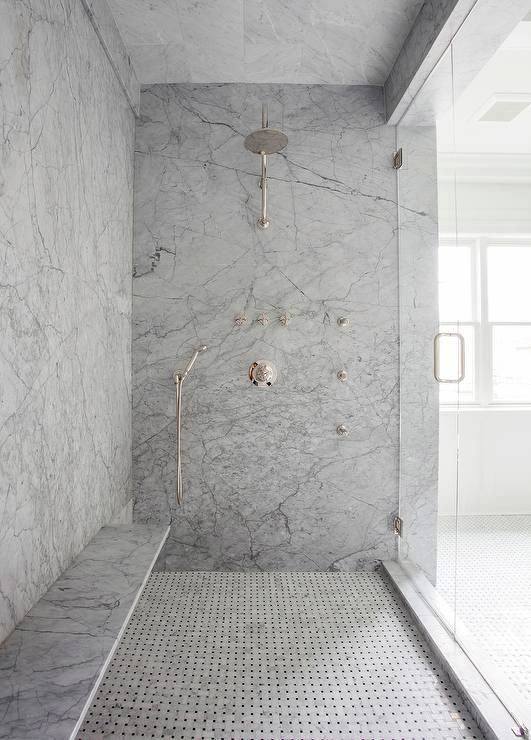 Modern marble shower with rainfall showerhead, built-in bench, and glass door.