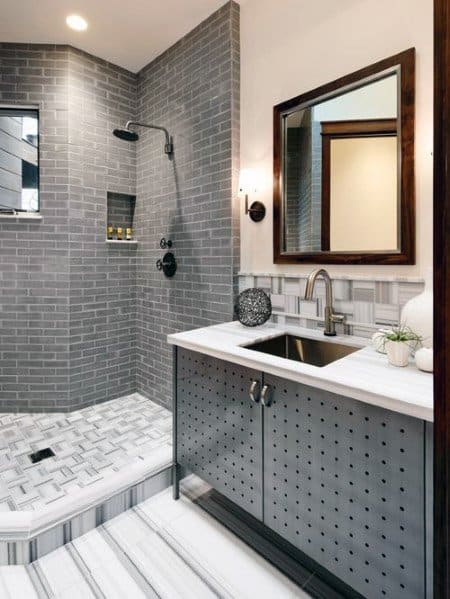 Modern bathroom with gray tiles, walk-in shower, and a vanity with a mirror and sink