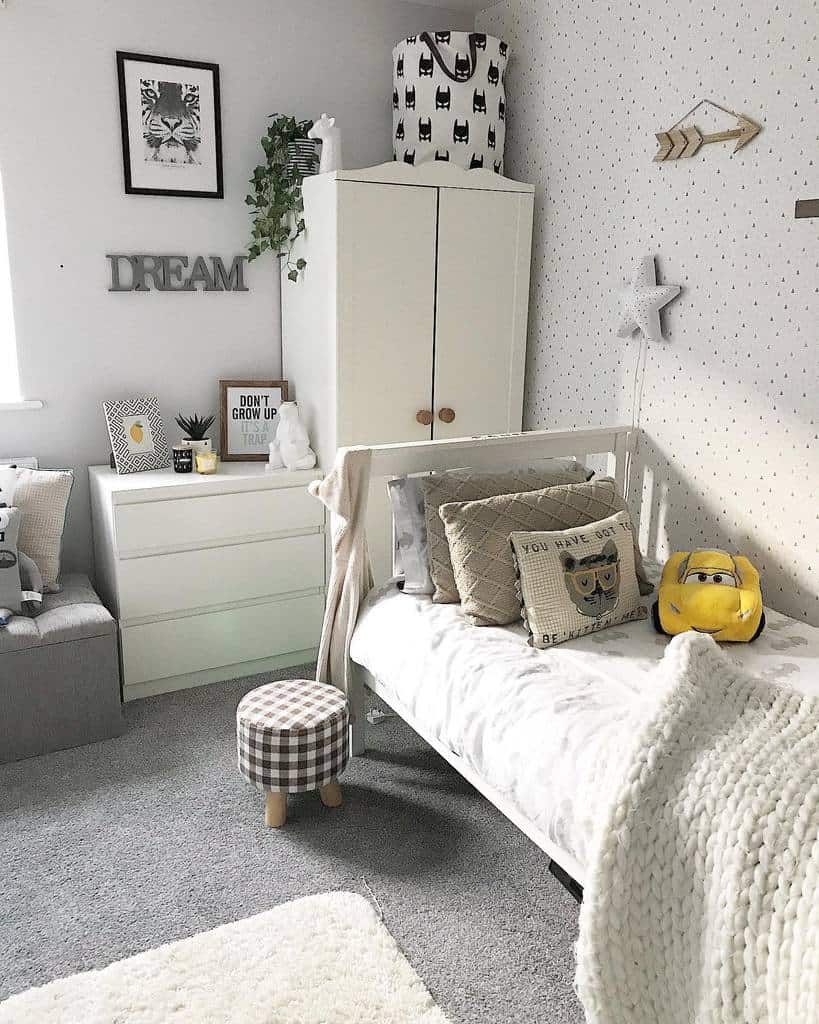 Kids' room with simple printed wallpaper, white furniture, and cozy decor accents.