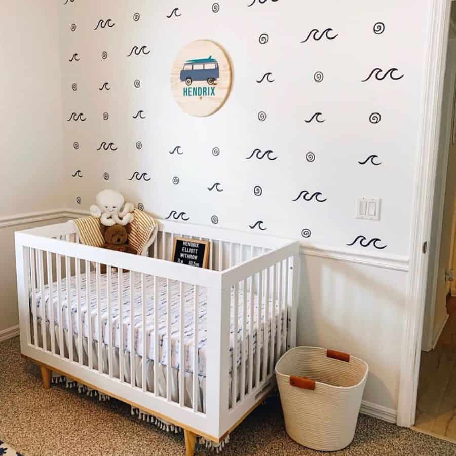 Simple nursery with playful wall decals, personalized decor, and a cozy white crib.