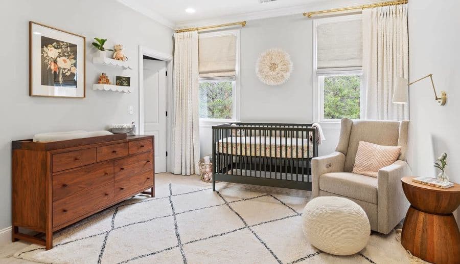 Country-themed nursery with wooden dresser, gray crib, plush armchair, and soft neutral accents.