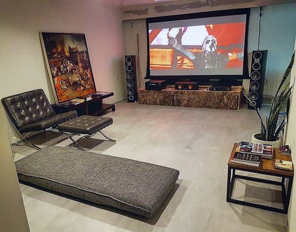 Minimalist mancave home theater with large projector screen, modern lounge chair, and simple decor.