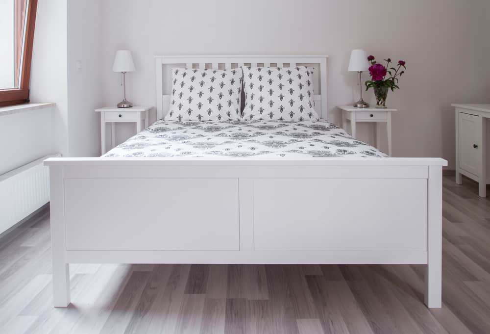 Minimalist bedroom featuring a white bed, bedside tables, and floral decor.