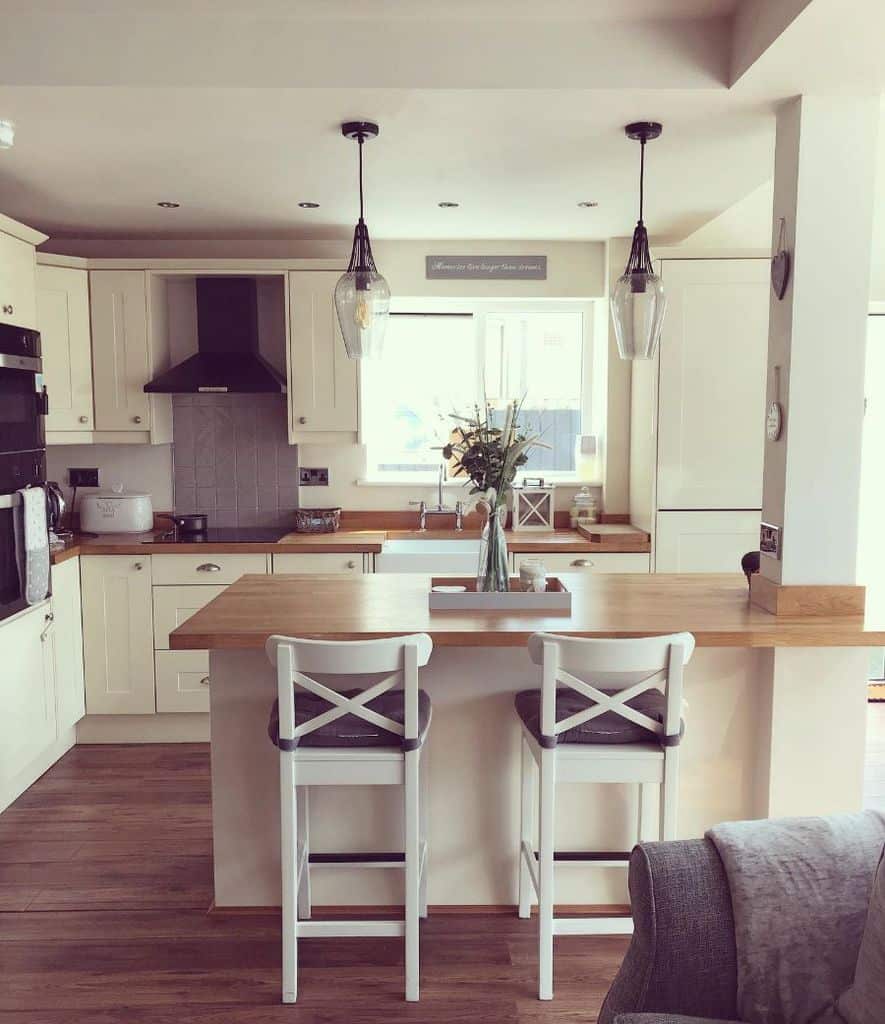 simple white kitchen bar with wood countertop pendant lights