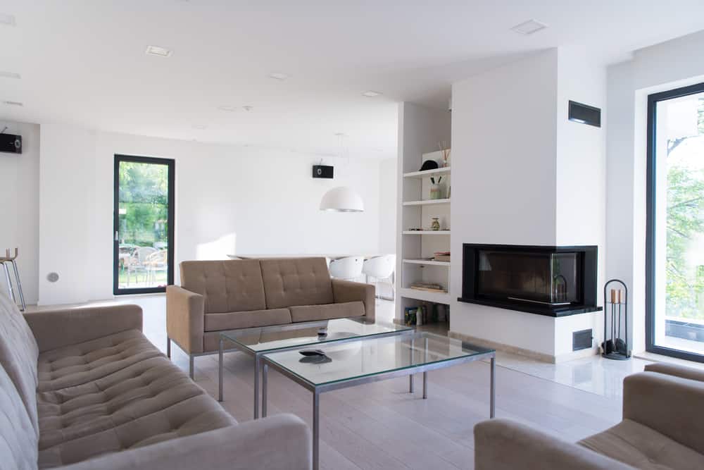 Minimalist living room with a clean design, featuring a glass coffee table, neutral sofas, and a cozy built-in fireplace