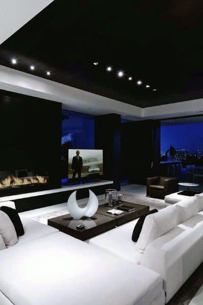 Contemporary living room with white sofas, dark ceiling, fireplace, and large windows showcasing a night cityscape