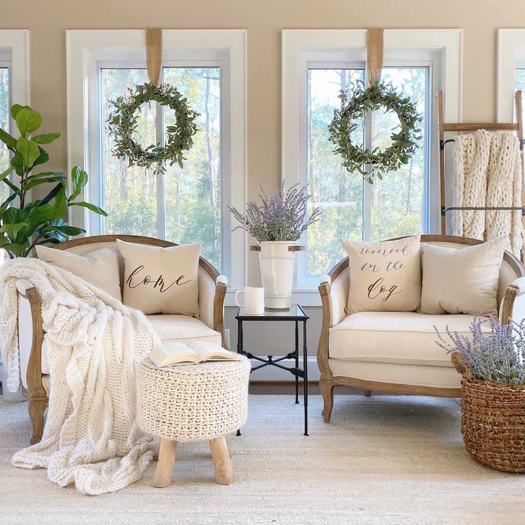 Cozy sunroom with neutral armchairs, knit blankets, wreath decor, lavender accents, and greenery.