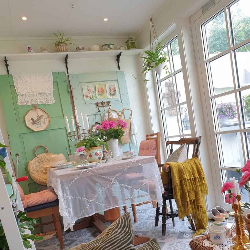 Vintage sunroom with wooden chairs, pink cushions, and a yellow throw blanket.