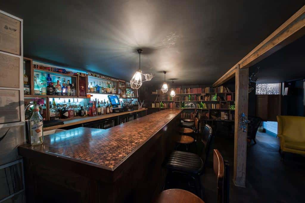 Cozy wet bar with a unique penny countertop, dim lighting, and bookshelf decor.