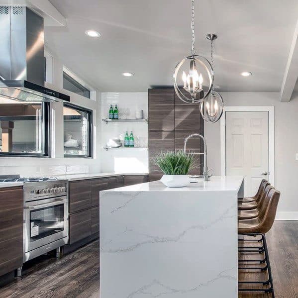 Modern kitchen with sleek orb pendant lights hanging above a white marble island, complemented by dark wood cabinetry and minimalist decor