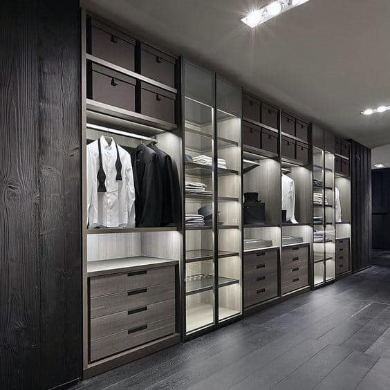 Modern walk-in closet with neatly organized clothes, shoes, and boxes on illuminated shelves and drawers