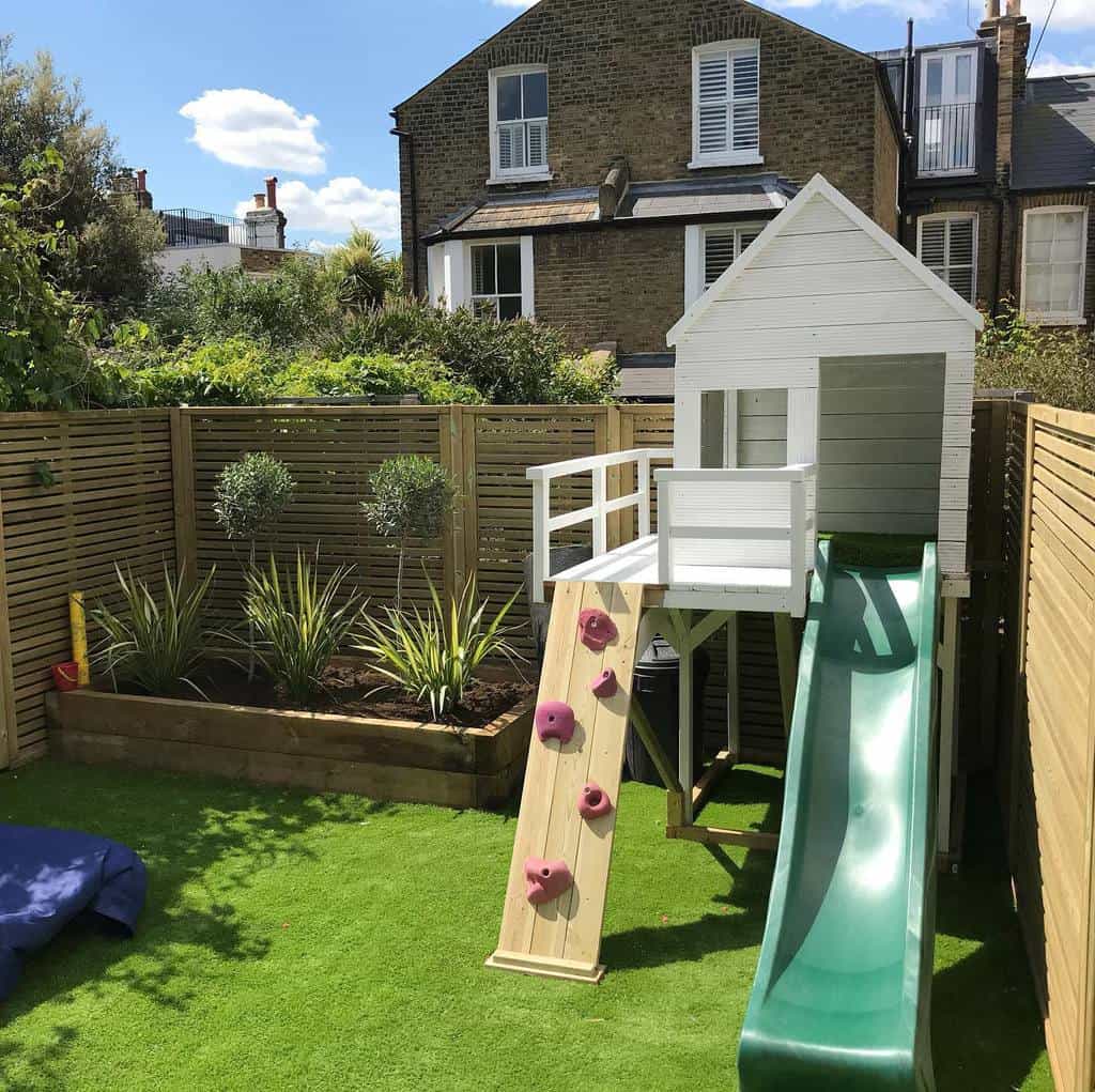 small backyard with astroturf and treehouse with slide 