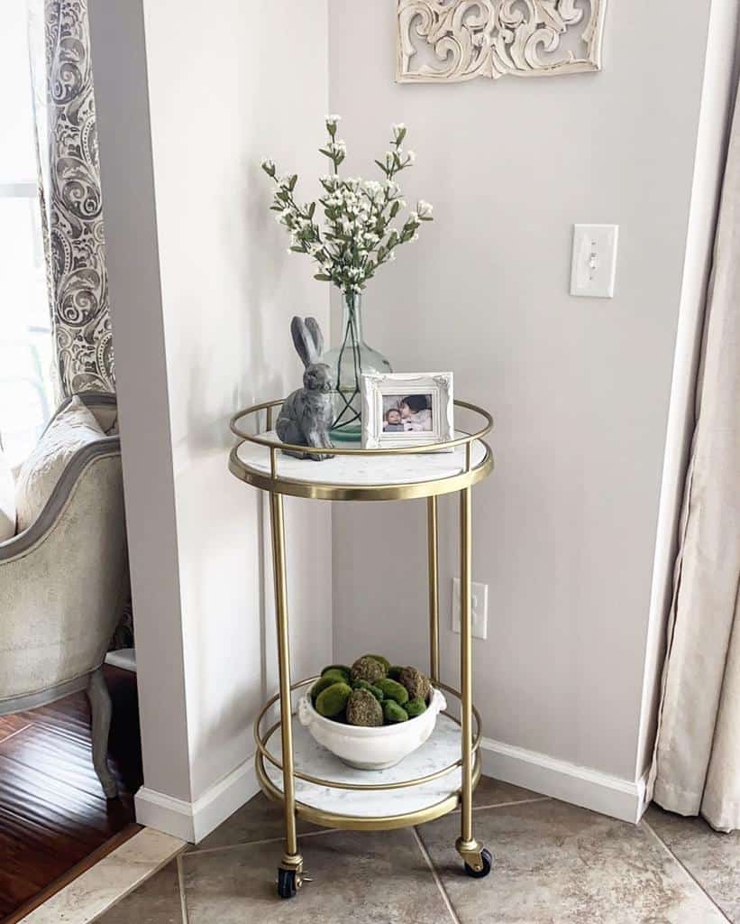 Small gold bar cart with vase, bunny figurine, framed photo, and bowl of moss decor.