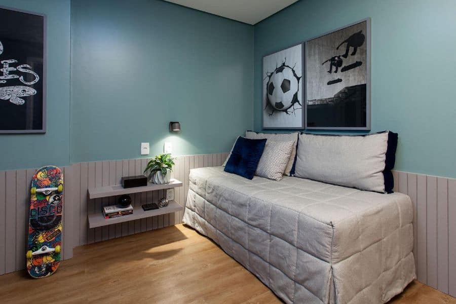 Modern bedroom with small couch, wall shelves, skateboard decor, and sports-themed art.