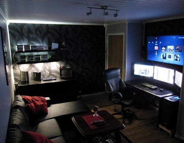 Modern gaming setup with multiple screens, black furniture, and LED lighting in a dimly lit room