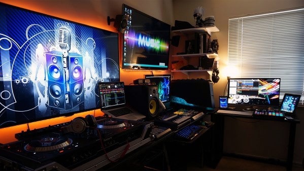 Home music studio with multiple screens, DJ equipment, and vibrant lighting