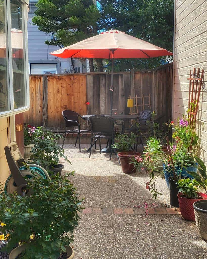 small backyard black table and chairs red umbrella potted plants 