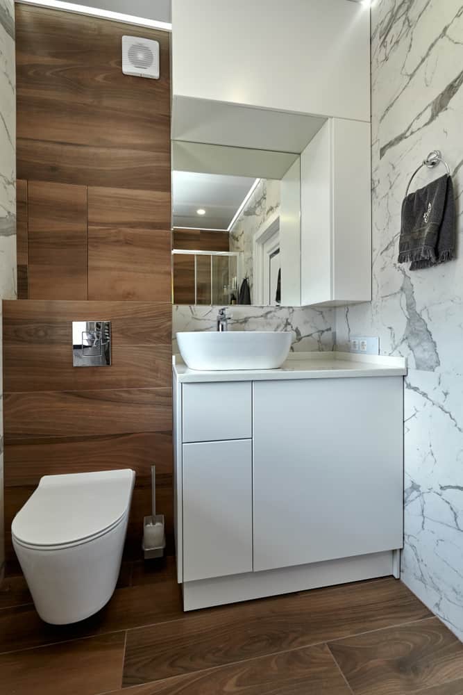 Modern bathroom with marble walls, wood accents, and white vanity with vessel sink.