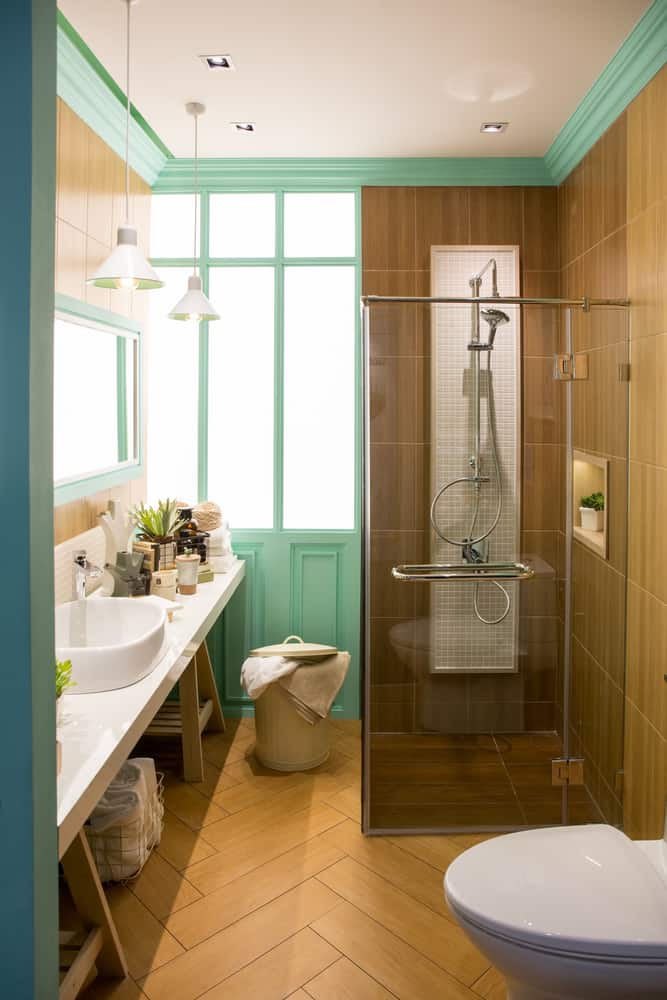 Modern bathroom with wooden tiles, teal accents, glass shower, and sleek vanity design.