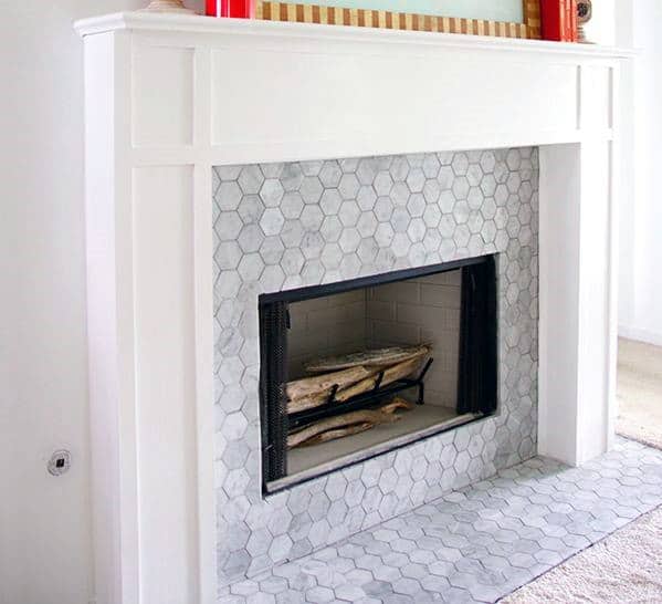 White fireplace with gray hexagon tiles and a simple wooden mantel.