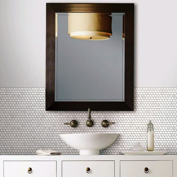 White hexagon tile backsplash with round vessel sink and dark framed mirror above.