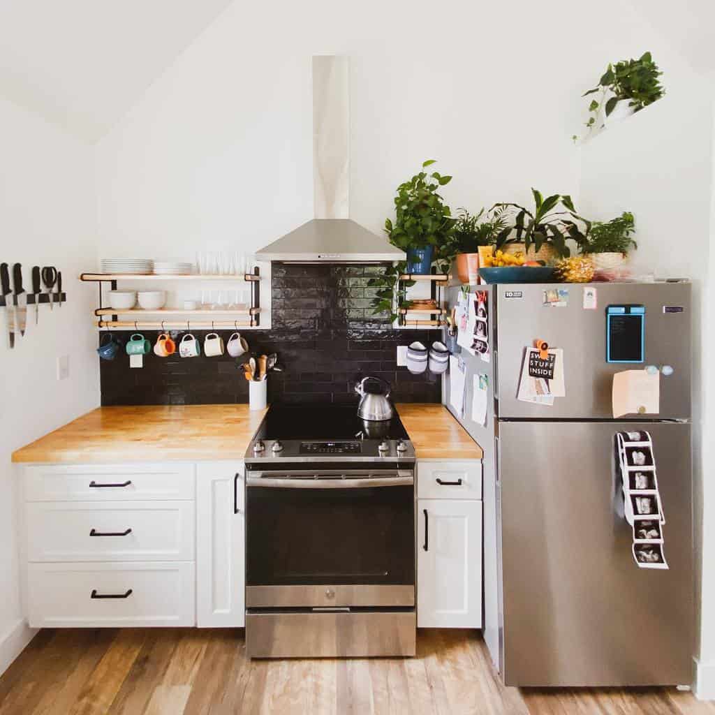 small country style kitchen white cabinets floating wall shelves black tile backsplash 