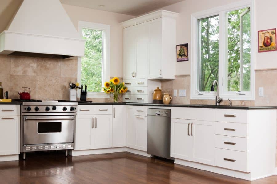 small corner kitchen with white cabinets and tile backsplash 