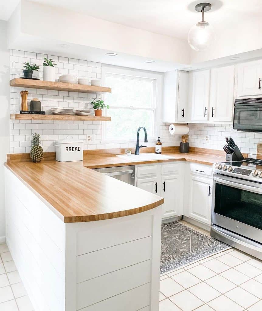 bright small white cabinet kitchen with wood countertop and white tile backsplash 