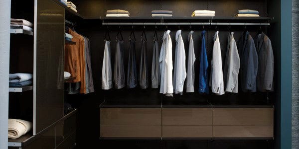 A neatly organized closet with shirts on hangers and folded clothes on shelves