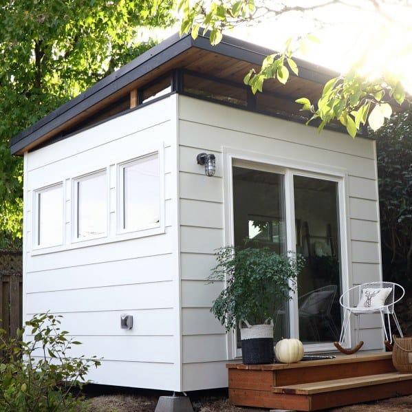 odern office shed with sliding glass door, white siding, and small front porch.